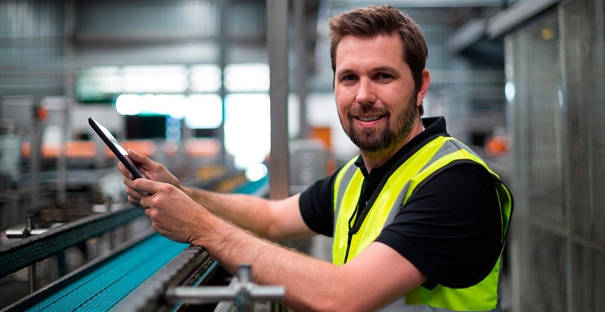 Ingeniero de organización industrial supervisando línea de producción con tablet