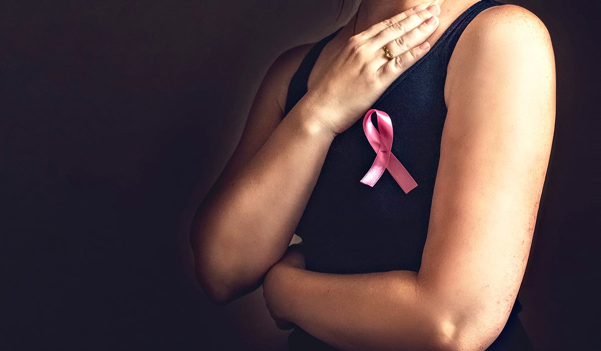Mujer con lazo rosa sobre el pecho, símbolo de lucha contra el cáncer de mama.